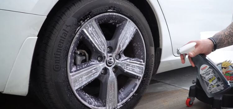 Spray Sonax Wheel Cleaner onto the wheels, covering the entire surface.